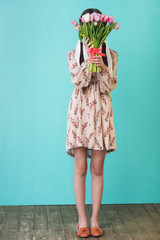 stylish girl in summer dress holding tulips, on blue