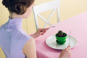 female teenager eating cactus with fork and knife, diet concept