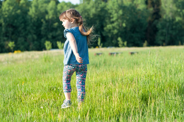 Little girl running in the meadow, back view