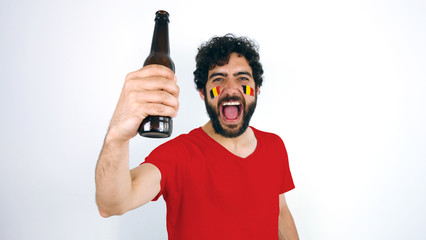 Sport fan holding a beer screaming for the triumph of his team. Man with the flag of Belgium makeup...