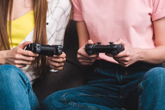 cropped image of two female friends  with joysticks in hands playing video game