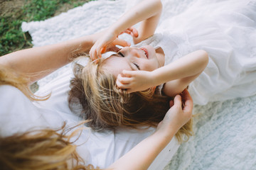 Portrait of cute little smiling girl lying on knees of her mother