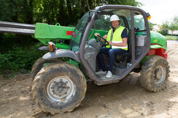 male heavy equipment operator sitting in cab of track-hoe at construction site
