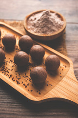 Nachni laddu or Ragi laddoo or balls made using  finger millet, sugar and ghee. It's a healthy food from India. Served in a bowl or plate with raw whole and powder. Selective focus