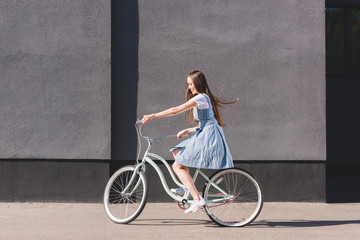 side view of young happy woman riding on bicycle
