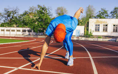 Fototapeta premium Professional young sprinter athlete male at starting position ready to start a race. Man sprinter ready for sports exercise on racetrack in stadium. Sport, lifestyle and people concept.