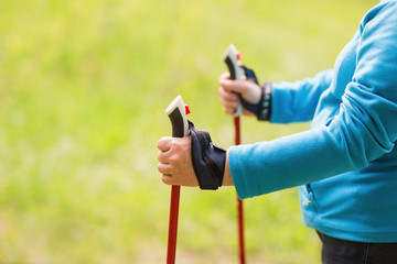 Nordic walking exercise adventure hiking concept - closeup of elderly woman's hand holding nordic walking poles.