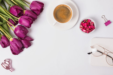 Tulips, coffee and feminine accessories on the white table.