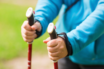 Nordic walking exercise adventure hiking concept - closeup of elderly woman's hand holding nordic walking poles.