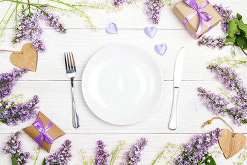 Festive table setting with cutlery and spring flowers on white wooden table.