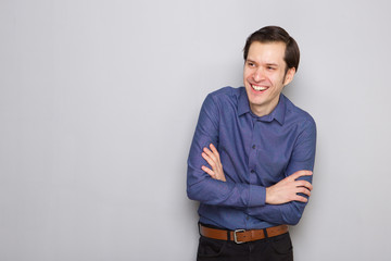 smiling young male employee standing with arms crossed