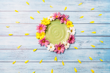 summer background: green plate surrounded by gerbera flowers on a blue background