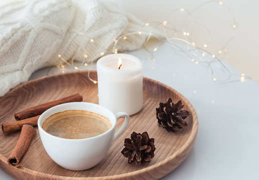 Winter morning concept. Coffee, candle and pine cones on the tray.