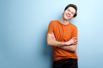 Fashionable laughing man standing by blue wall