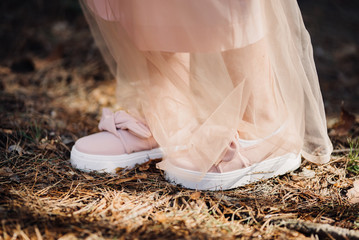 hem of pink long dress and pink sneakers on legs