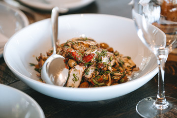 hot vegetable salad with mushrooms and olives in a white plate on the table.