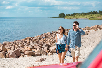 Fototapeta premium beautiful couple of travelers holding hands and walking near the sea
