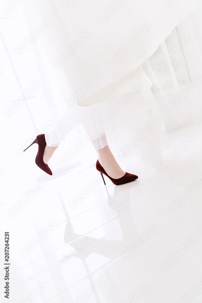 Wall mural close-up of the bride's legs in red shoes. Reflection of the legs of a woman in shoes on tiles