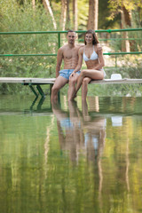 Active couple rests on river bank on a hot summer day