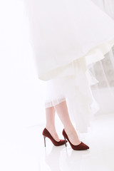close-up of the bride's legs in red shoes. Reflection of the legs of a woman in shoes on tiles