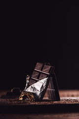 closeup shot of two arranged chocolate bars on wooden table on black background