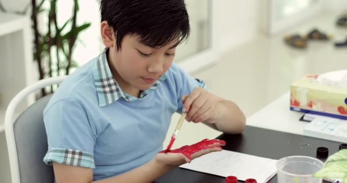 Happy asian cute child painting water colour on your hand with smile face.