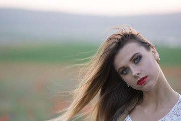 Fototapeta premium Pretty young blonde walking on a poppy fields