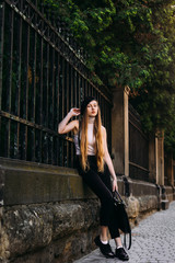 beautiful girl in a black and white dress against a metal fence