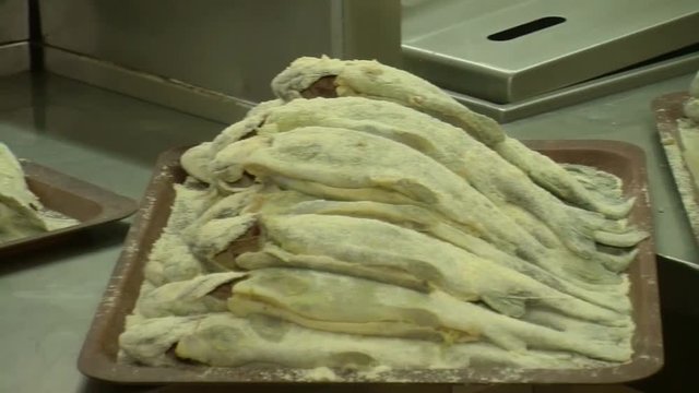 Fish fried in a frying pan until golden brown,Pieces of fresh fish are fried in a frying pan in flour and they are turned with a fork.Chef is cooking fish.Preparing of fish for frying.