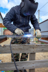 Welder welds metal at the construction site