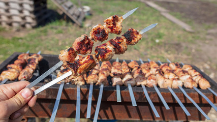 Meat roasted on sticks on charcoal in hand