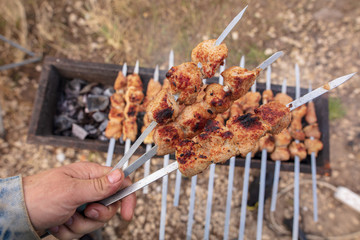 Meat roasted on sticks on charcoal in hand