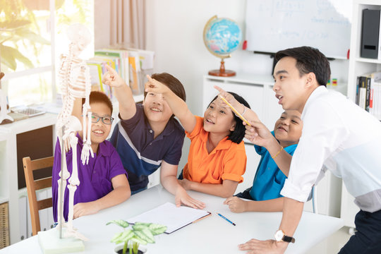 Asian teacher explains a human body structure to little pupil. - Powered by Adobe