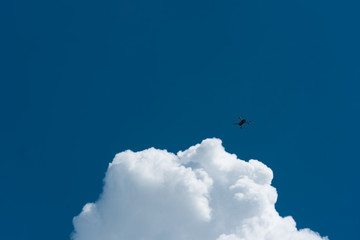 Drone flying high with blue cloudy sky in the background.