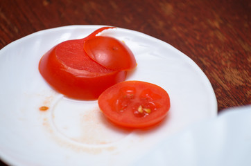 Sliced tomato slices left after dinner on a white plate on the table. Dirty dishes.