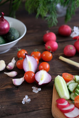 Fresh vegetables sliced for a salad on a cutting board, on an old wooden table