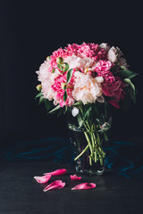 beautiful bouquet of pink peonies in glass vase on dark background