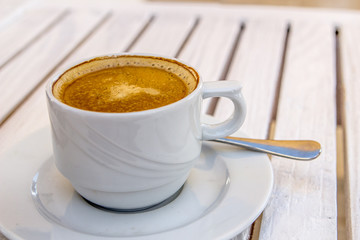 white cappuccino cup on a white wooden table on a sunny summer
