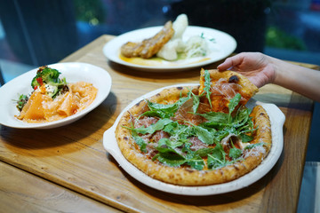 Homemade pizza with prosciutto (Parma ham), rocket leaves and parmesan cheese on wooden table background.