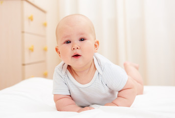 Portrait of beautiful child crawling on the bed at home. Baby care concept. 