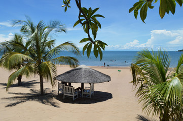 White wooden bungalow surrounded by palm leaves on the beach of amazing lake Malawi or Nyasa in Africa. Perfect peaceful sunny day on the beach of turqouise lake. - obrazy, fototapety, plakaty