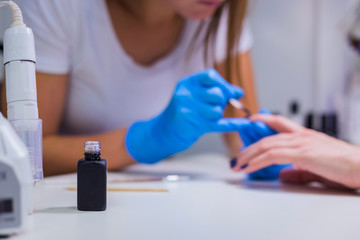 Nails painting with brush in nail salon on woman hands, focus on tube