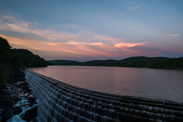 Sunset and reflection over water with dam and waterfall