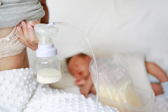 Automatic breast pump. Mothers breasts milk for newborn baby in bed room at home.