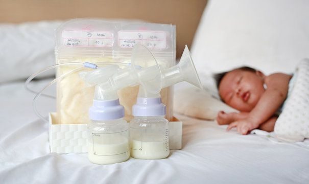 Breast pump and Frozen breast milk in plastic bag on the bed.
