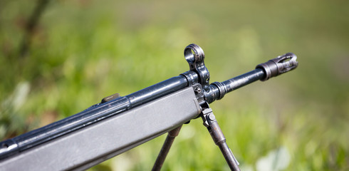 Shotgun on easel. Front side of weapon with close up view on blurred nature background.