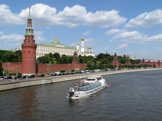 Obraz premium Tourist motor ship on the Moscow river on the background of the Kremlin towers. Kremlin embankment in summer, tourism in Russia