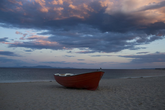 Boat on sand beach on cloudy evening sky. Fishing boat at sea shore after sunset. Summer vacation on sea. Fishing and recreation in tropic. Travel by water and wanderlust