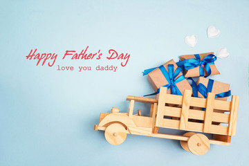 Father's Day greeting message with wooden toy truck with gift box in the back on blue background. - Powered by Adobe