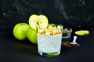 Healthy chia pudding with apples and granola in glass.